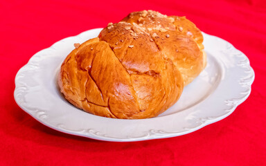 tsoureki, traditional Greek sweet bread served on white plate and red fabric background