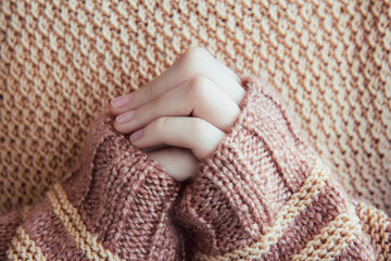 Woman in a beige soft warm knitted sweater hold hands together is symbol prayer and gratitude