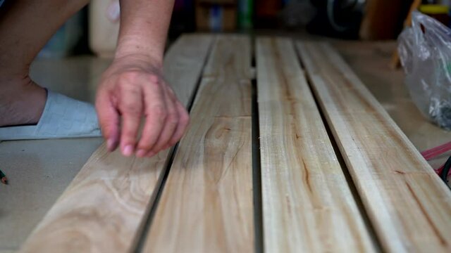 A worker is hitting a nail on a wooden board with a hammer