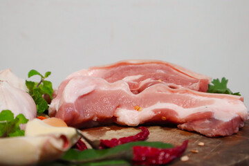 The focus is on fresh, bright red pork on a cutting board prepared by the chef to season