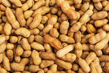 Background of unpeeled peanuts in the shell. Full frame top view of the scattered nuts. Beautiful texture of the food. Selling peanuts at the farmers ' market. Macro photography of nuts. Harvest.