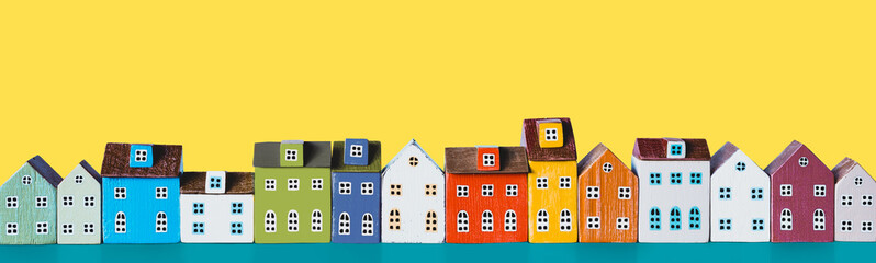 Row of wooden miniature colorful retro houses on a yellow background