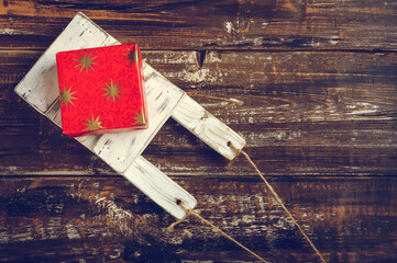 Old wooden toy sled with gift boxes on  wooden background.