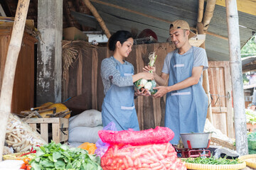 vegetable seller wearing an apron stands carrying vegetables at a vegetable stand