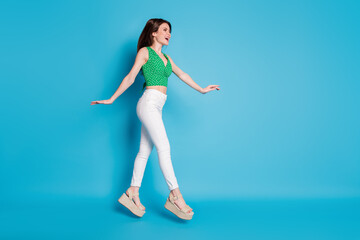 Full length profile side photo of dreamy carefree girl jump go walk copyspace enjoy free time wear good look outfit isolated over blue color background