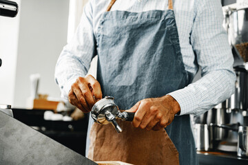 Unrecognizable man barista preparing coffee on professional coffee machine