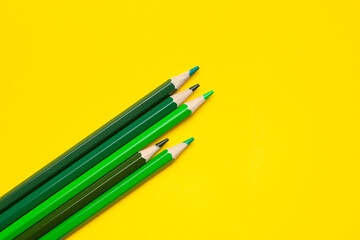 diagonal green sharp wooden pencils on a bright yellow background, isolated, copy space, mock up.