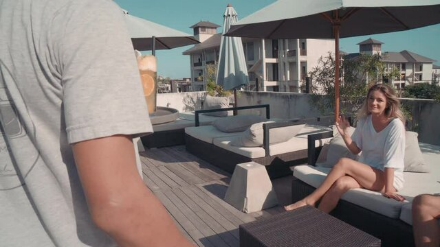 Tracking Shot Of Waiter Serving Cocktails To Young Couple In Poolside Talking And Relaxing