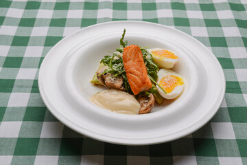 Grilled red fish steak and boiled eggs served in a white plate over green plaid tablecloth. Italian cuisine, concept.