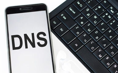 DNS - Acronym Domain Name System is an inscription on the phone screen that lies on the laptop...