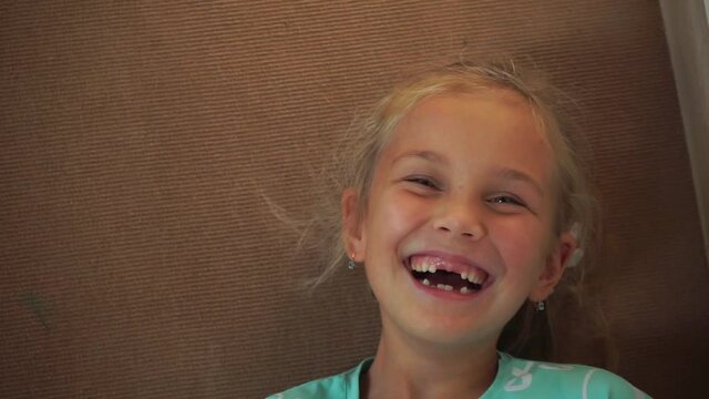 Happy little blonde lies on the floor and laughs contagiously in a full voice, toothless childish smile, childish laughter