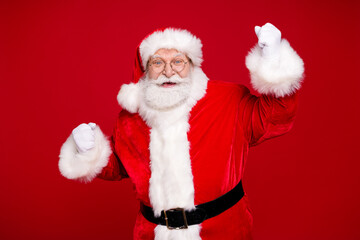 Photo of pensioner grandpa grey beard raise fists win shocking discount newyear shopping wear santa costume leather belt gloves coat spectacles headwear isolated red color background