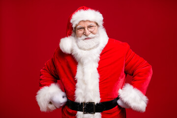 Photo of retired old man grey beard fists hips self-assured attend educate naughty kid play strict grandpa wear santa costume belt coat spectacles headwear isolated red color background
