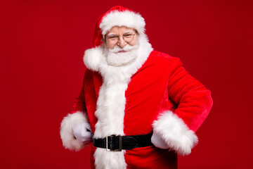Photo of retired old man grey beard hands hips self-assured look prepare listen children wishes event wear santa costume belt coat spectacles headwear isolated red color background