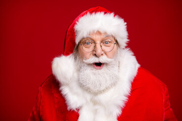 Photo of retired old man grey beard open mouth amazed look see children sing christmas carol want gift prepare present wear santa costume coat spectacles headwear isolated red color background