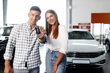 Young happy couple just bought a new car in a dealership