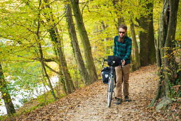 Obraz premium Attractive hipster man with bicycle at a public park during autumn.