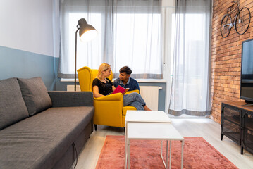 Young couple looking each other with a shy smile at living room.