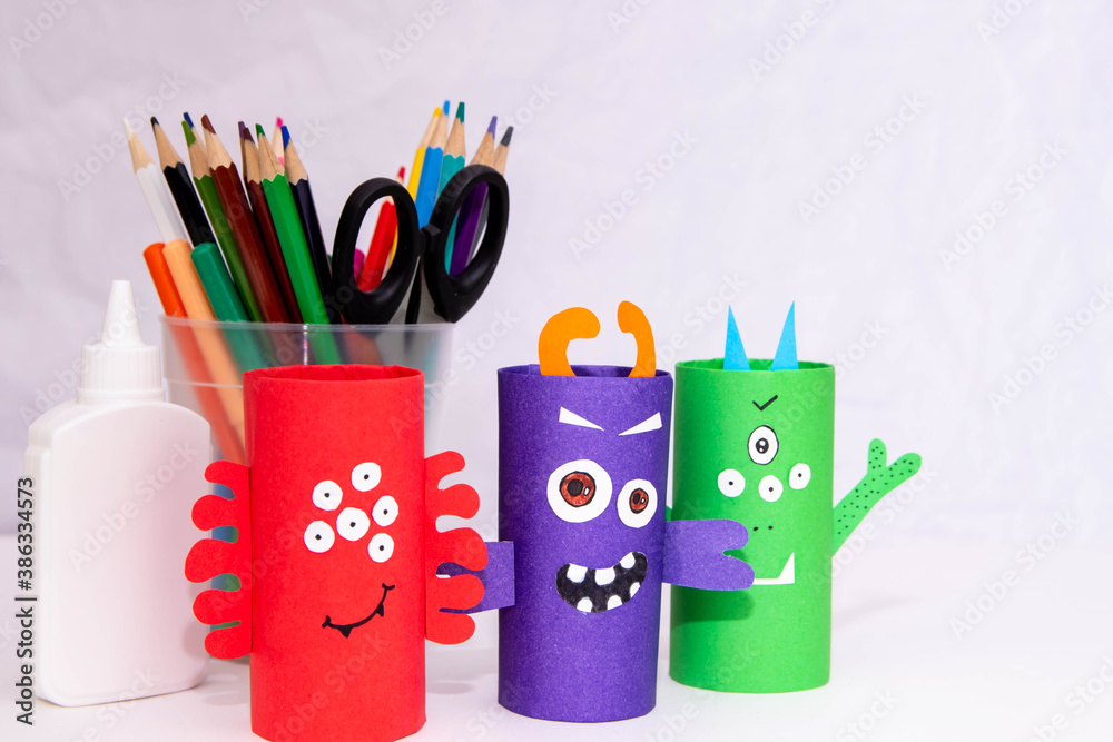 Wall mural Halloween decoration. DIY and kids creativity concept. Monsters from toilet rolls and colored paper on a white table.