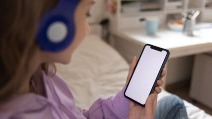 Close up view of Caucasian teenage girl look at white mockup smartphone screen chat text on gadget. Smart teenager use cellphone device, talk speak on video call online, browse wireless internet.