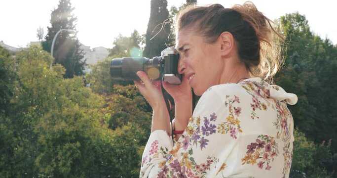 Woman having a calm walk in Madrid and taking pictures of the city with a vintage camera