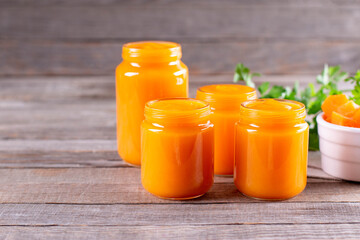 Autumn winter food. Pumpkin puree in glass jars. Wooden background, copy space