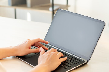 Freelance work. Remote job. Online communication. Business correspondence. Female blogger hands typing on laptop with blank black screen at light office desk.