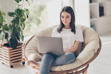 Photo of smart girl sit wicker armchair work laptop wear white t-shirt denim jeans in house indoors