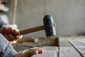 Man laying paving stones on the floor using a rubber mallet