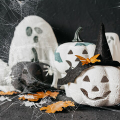 Happy halloween holiday. Halloween decorations, black and white pumpkins, bats, ghosts on a black background. Halloween party greeting card mockup with copy space. Halloween greeting banner