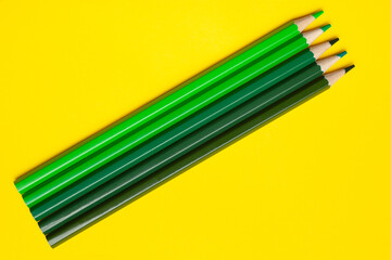 diagonal green sharp wooden pencils on a bright yellow background, isolated, copy space, mock up.