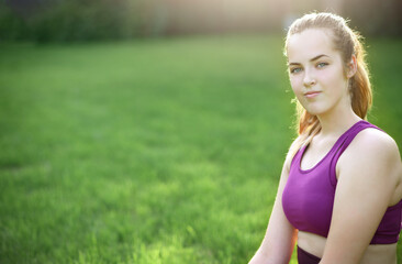 Fototapeta na wymiar Portrait of Young sporty woman in sport dress does stretching exercises outdoor. Sunny. Outside, exhausted. High quality photo