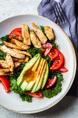 Chicken salad with tomato, avocado and kale in gray bowl, top view. Diet food concept.
