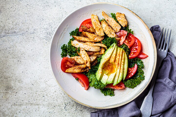 Chicken salad with tomato, avocado and kale in gray bowl, top view. Diet food concept.