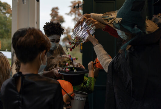 Hosts giving candies to a group of trick-or-treating kids during Halloween