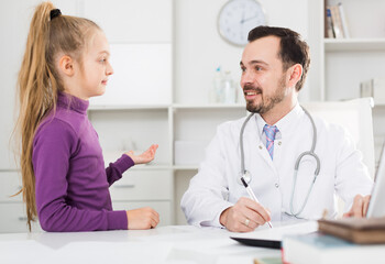 Little smiling girl visiting consultation with man doctor in hospital