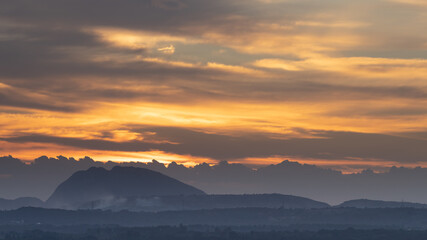 Silhouette of a hill against beautiful golden hour light and beautiful clouds formation in the horizon
