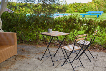 Obraz premium A bucket of pine cones on an empty garden table and two chairs