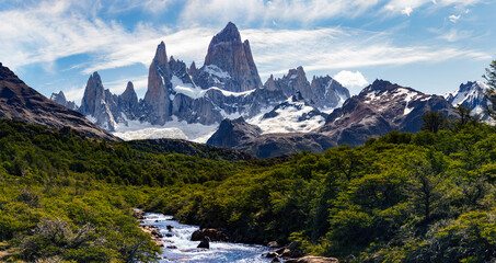 Wald, der vom Gletscherfluss im Nationalpark El Chalten, Argentinien, Patagonien mit dem Berg Fitz Roy und dem Cerro Torre im Hintergrund durchquert wird