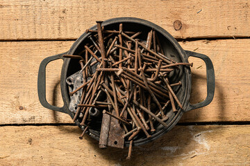 old nails in a box, curving and rusty in a heap on a wooden background