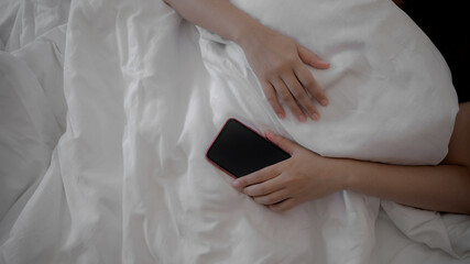 Mobile phone and social media addiction, Woman hand holding smart phone during sleeping.