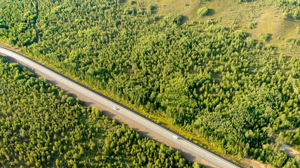 Aerial view over a rural road with two cars driving opposite each other.