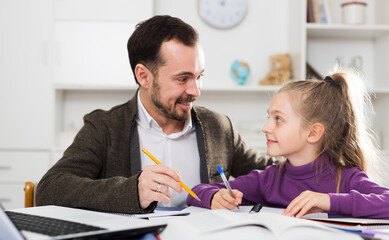 Young father helping his daughter to prepare homework at home