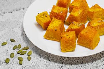 Baked pumpkin in a white plate. Side view. Pumpkin cooked in the oven. Cut pieces of pumpkin.A traditional autumn dish of baked pumpkin. Close-up.