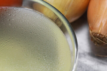Chicken broth in a transparent plate on the background of vegetables. Close-up. Clear chicken broth. Meat broth. Broth for the disease. Vegetable broth.