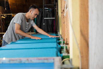 The workers level by hand the uneven surface of the t-shirts when preparing the t-shirts that are placed on the board before screen printing