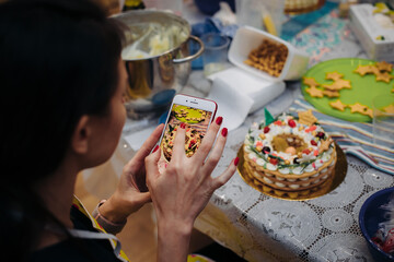 A pastry chef takes photos of a ready-made Christmas cake on his phone. new year's preparations.waiting for the holiday