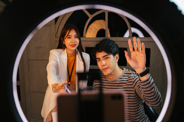 Famous influencers doing live stream with smartphone and warm light in studio.