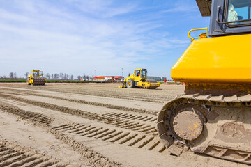 Plate compactor is mounted on road roller to compact soil at construction site