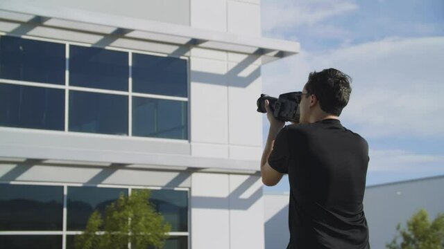 A photographer takes exterior shots of an office building for a location scout on a windy day.